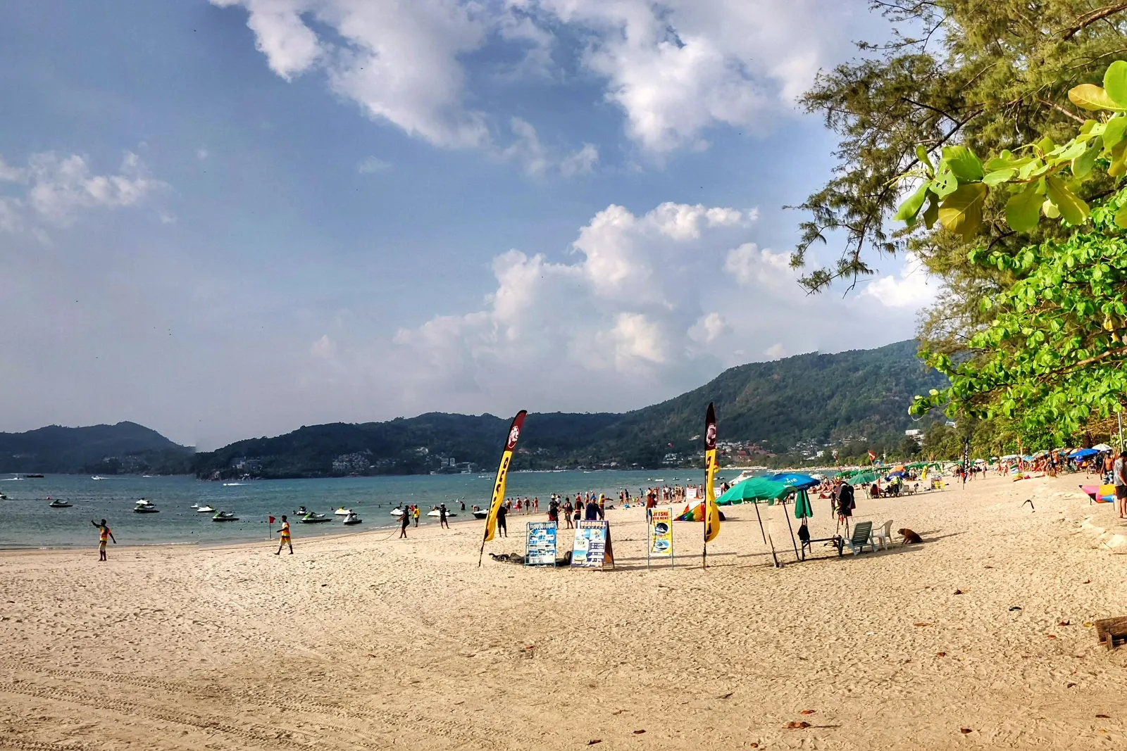 Patong Beach auf Phuket mit Sonnenschirmen und grünen Hügeln